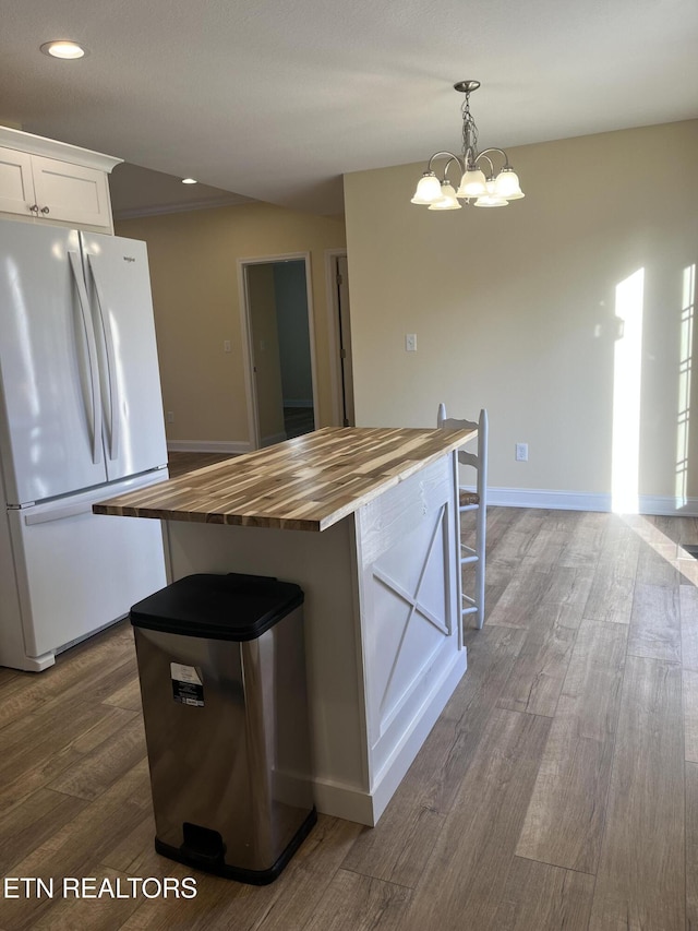 kitchen featuring wood counters, white refrigerator, dark hardwood / wood-style flooring, pendant lighting, and white cabinets