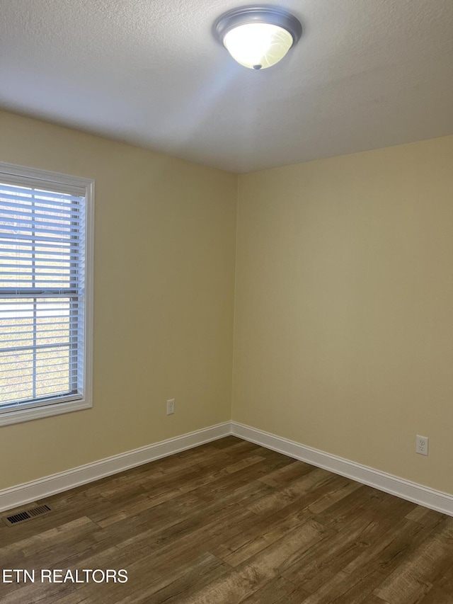 empty room featuring dark wood-type flooring and a textured ceiling