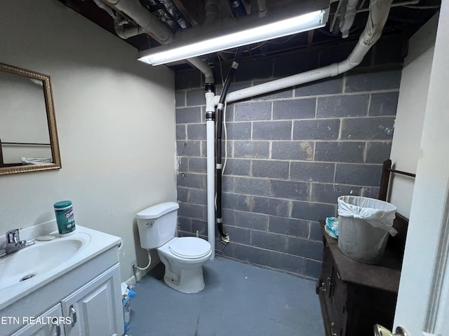 bathroom with toilet, vanity, and concrete flooring