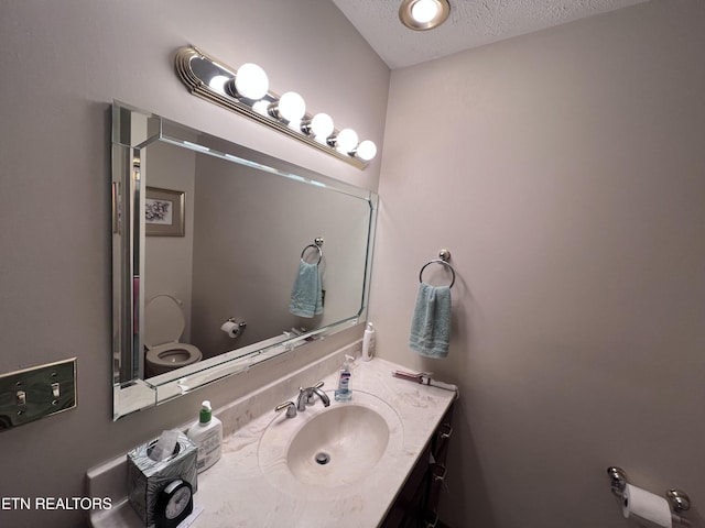 bathroom featuring vanity, toilet, and a textured ceiling