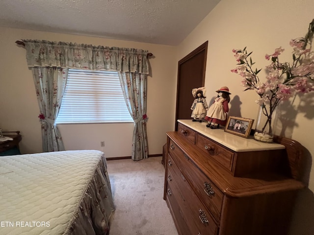 bedroom with light colored carpet and a textured ceiling