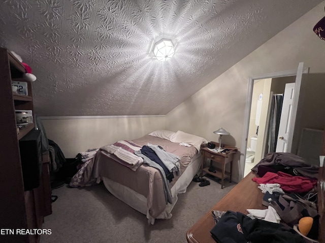 bedroom featuring lofted ceiling, ensuite bath, a textured ceiling, and carpet flooring