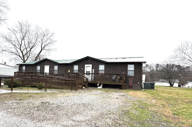 view of front of home featuring a wooden deck, a front yard, and central AC unit