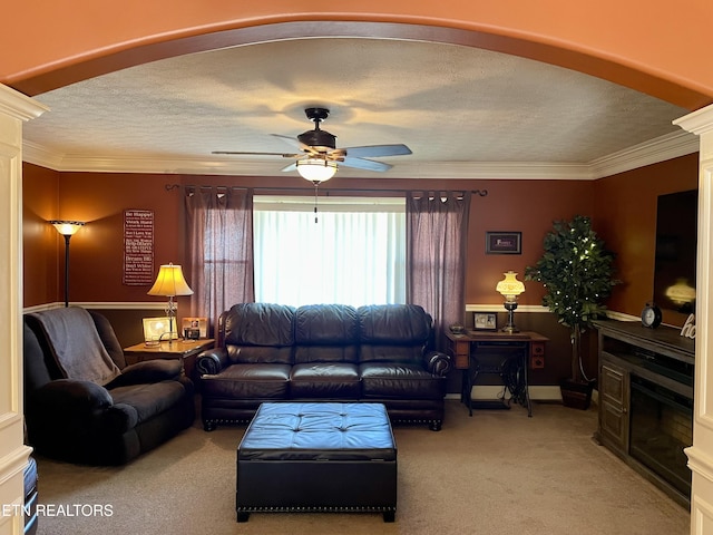 carpeted living room with ceiling fan, ornamental molding, decorative columns, and a textured ceiling