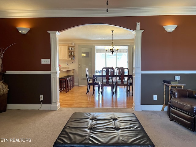 living room with crown molding, decorative columns, a chandelier, and carpet flooring