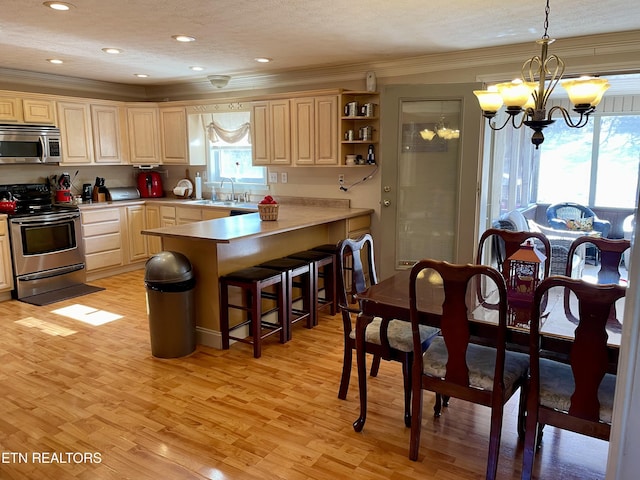 kitchen featuring pendant lighting, appliances with stainless steel finishes, a kitchen breakfast bar, ornamental molding, and kitchen peninsula