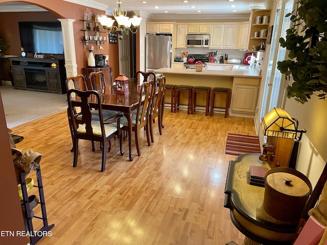 dining space featuring sink, a notable chandelier, ornamental molding, light wood-type flooring, and ornate columns