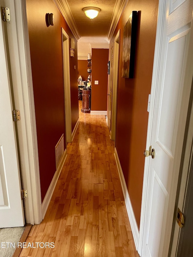 hallway with ornamental molding and light wood-type flooring