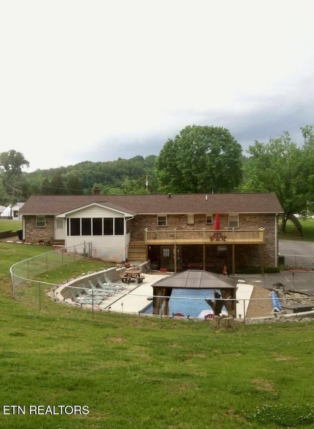 back of property featuring a patio area, a lawn, and a swimming pool side deck