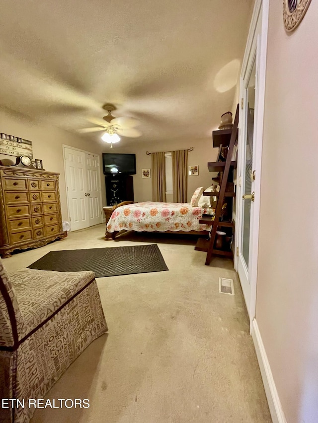 carpeted bedroom featuring ceiling fan and a textured ceiling