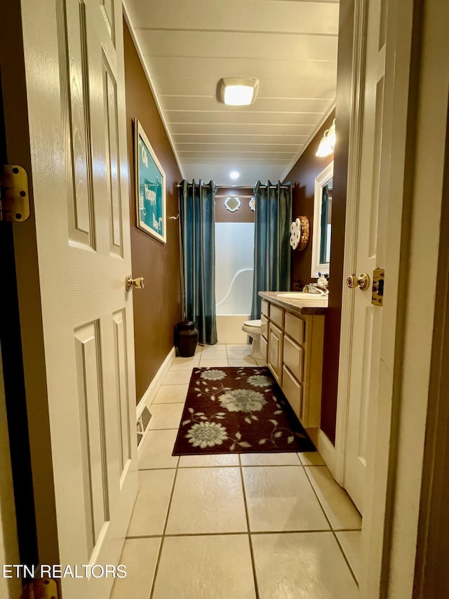 full bathroom with tile patterned floors, toilet, shower / bath combo with shower curtain, and vanity