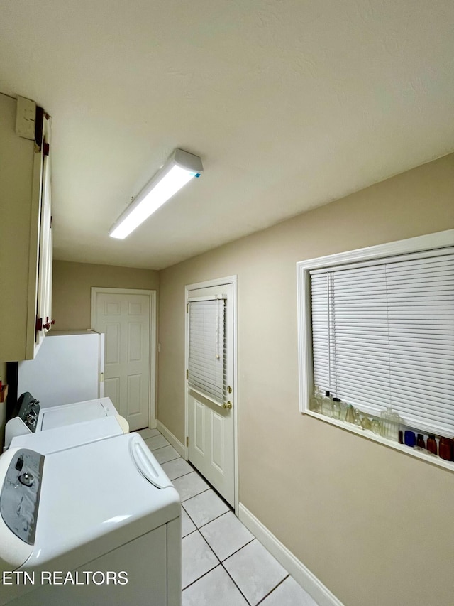 clothes washing area with cabinets, light tile patterned flooring, and independent washer and dryer