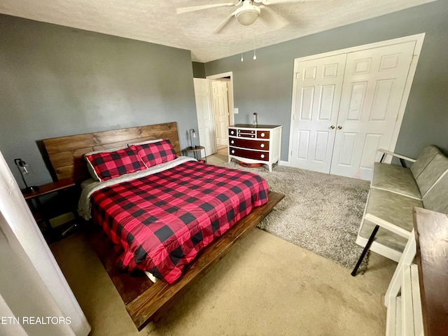 bedroom featuring ceiling fan, light colored carpet, a closet, and a textured ceiling