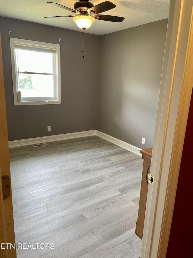 spare room featuring ceiling fan, a textured ceiling, and light wood-type flooring