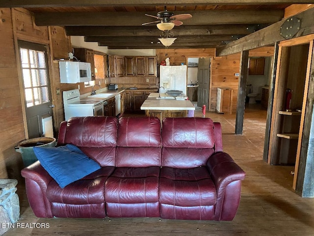 living room featuring sink, wooden walls, beamed ceiling, and ceiling fan