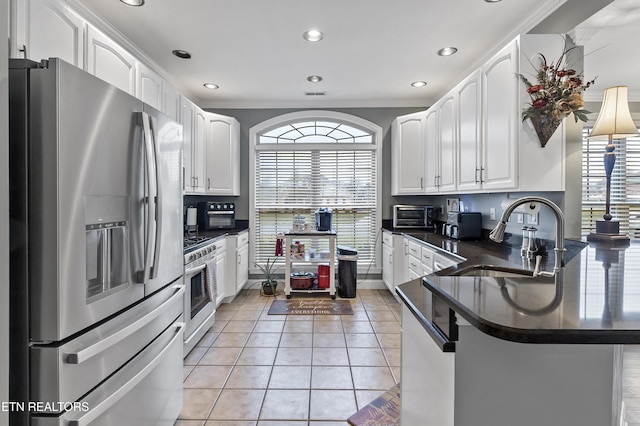 kitchen featuring stainless steel appliances, dark countertops, a sink, and a peninsula