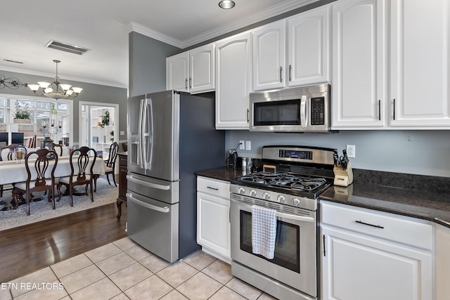 kitchen with light tile patterned floors, stainless steel appliances, white cabinetry, visible vents, and crown molding