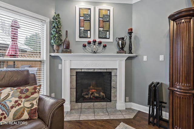 living room featuring a tiled fireplace, baseboards, and wood finished floors