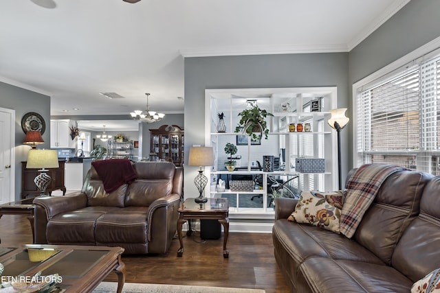 living area with crown molding, wood finished floors, visible vents, and an inviting chandelier