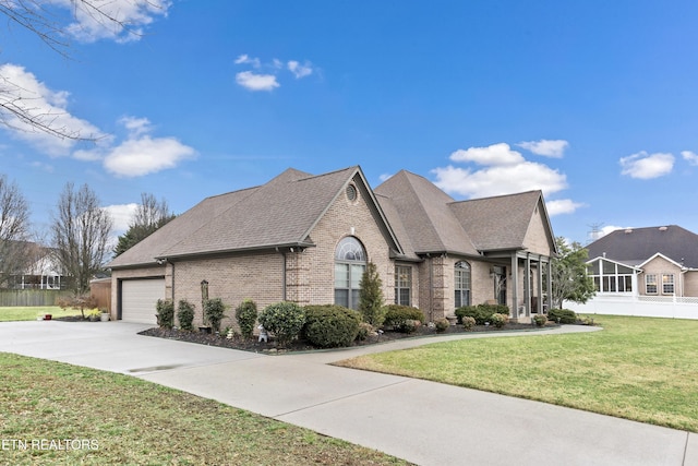 view of front of house with an attached garage, brick siding, a shingled roof, concrete driveway, and a front yard