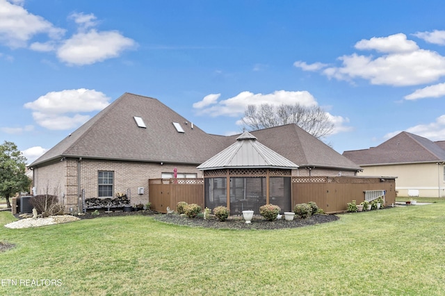 back of house with a yard, brick siding, roof with shingles, and central AC unit