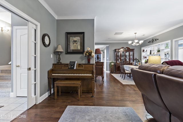 living room with crown molding, a notable chandelier, visible vents, wood finished floors, and stairs