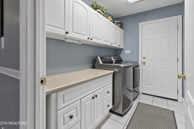 clothes washing area with cabinet space, washing machine and clothes dryer, and light tile patterned flooring