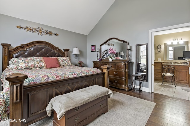 bedroom with light wood-type flooring, ensuite bath, and high vaulted ceiling