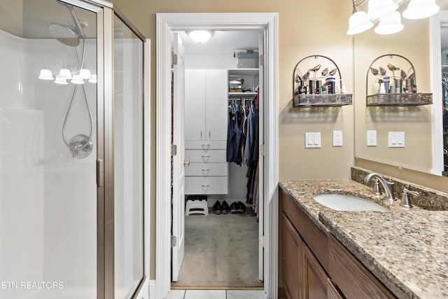 full bathroom featuring a spacious closet, a stall shower, and vanity