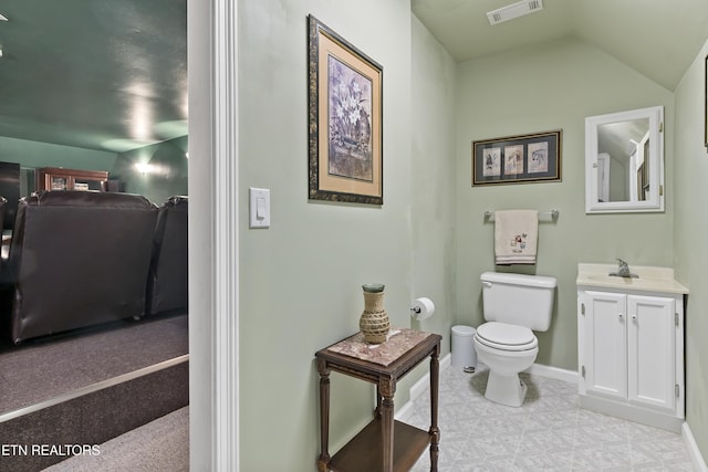 bathroom featuring toilet, vanity, visible vents, vaulted ceiling, and baseboards