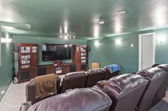 cinema room with a textured ceiling, carpet flooring, and baseboards