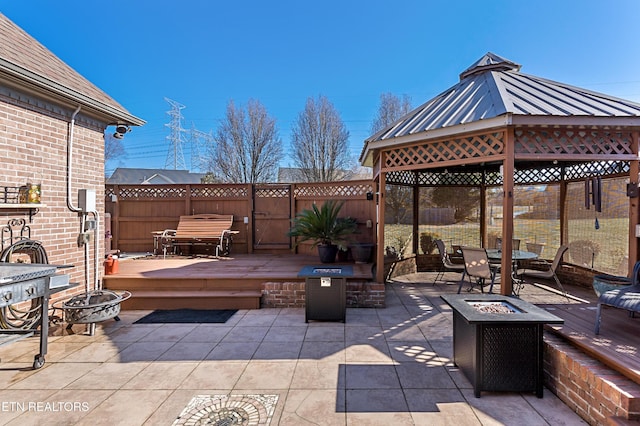 view of patio featuring a gazebo, an outdoor fire pit, a wooden deck, and fence