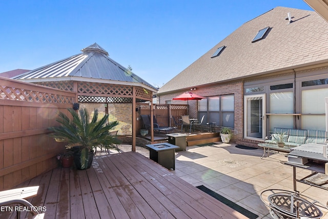 wooden deck featuring fence, a fire pit, a gazebo, and a patio