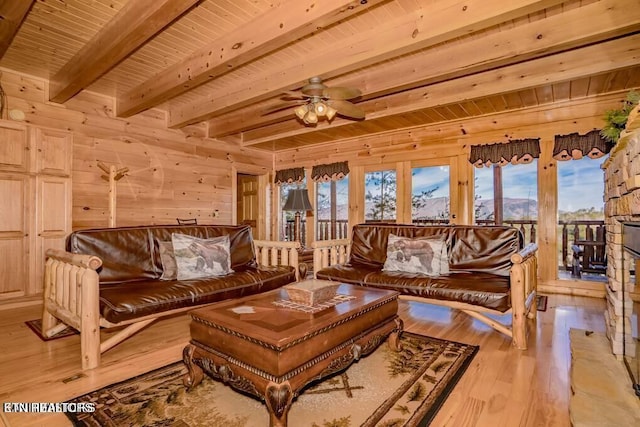 living room featuring a stone fireplace, wood walls, light wood-type flooring, wooden ceiling, and beam ceiling