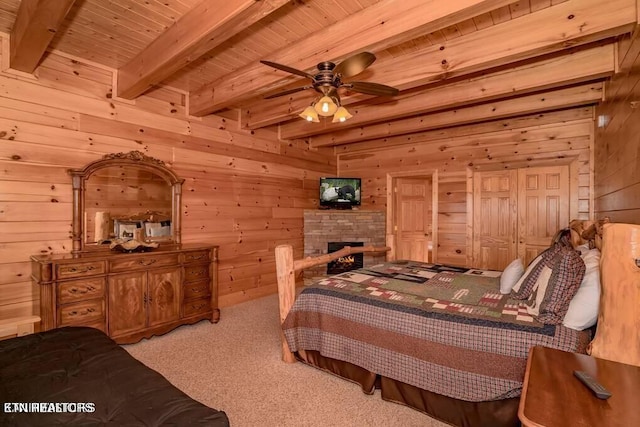 carpeted bedroom with beamed ceiling, wood ceiling, a stone fireplace, and wood walls