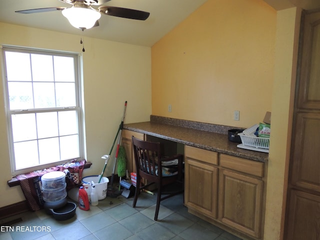 home office featuring built in desk, ceiling fan, and light tile patterned flooring