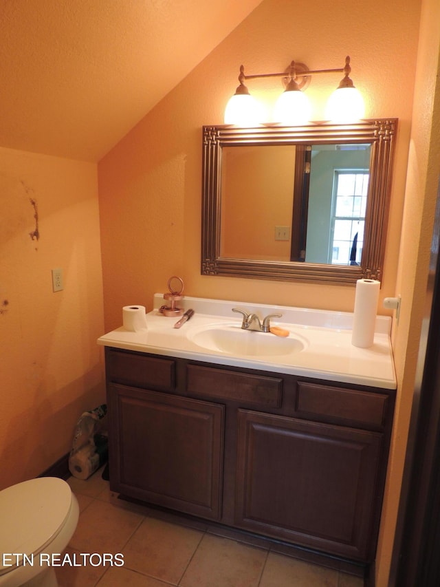 bathroom with vanity, lofted ceiling, tile patterned floors, and toilet