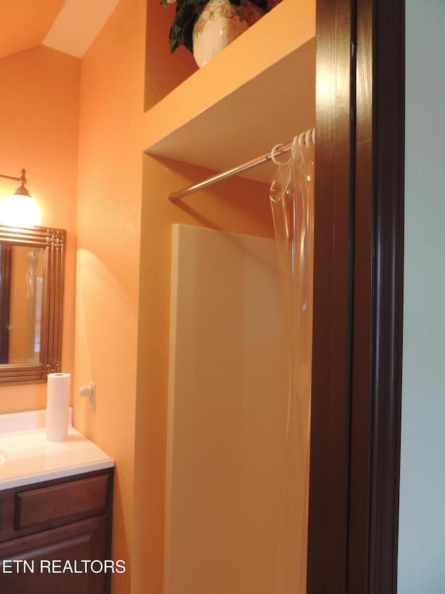 bathroom with vaulted ceiling, vanity, and a shower with curtain