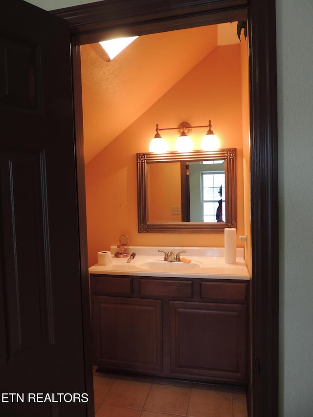 bathroom with vanity, vaulted ceiling, and tile patterned floors