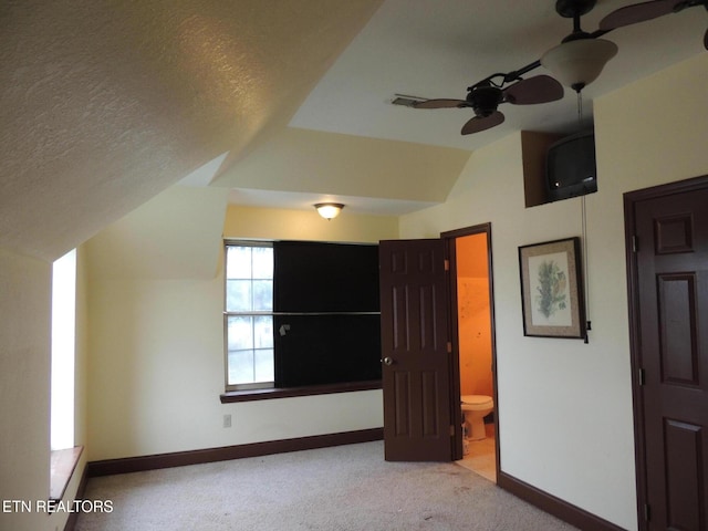 interior space with ceiling fan, vaulted ceiling, and a textured ceiling