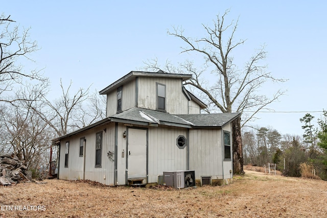 rear view of property with ac unit and a shingled roof