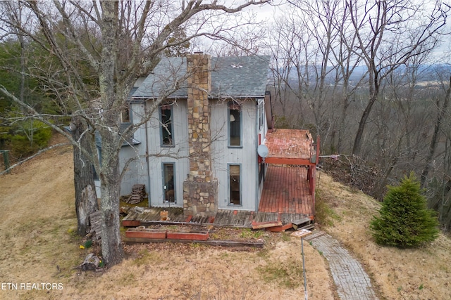 view of home's exterior with a chimney and a shingled roof