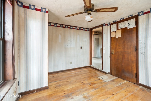 spare room with a ceiling fan, baseboards, wood-type flooring, and a textured ceiling