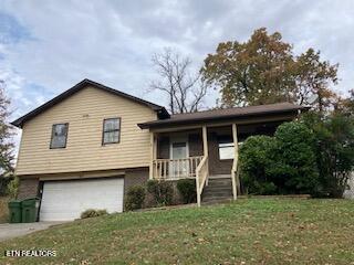 view of front of home featuring a garage, a porch, and a front yard