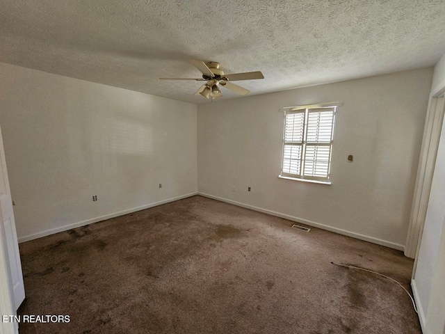 spare room with ceiling fan, a textured ceiling, and dark carpet