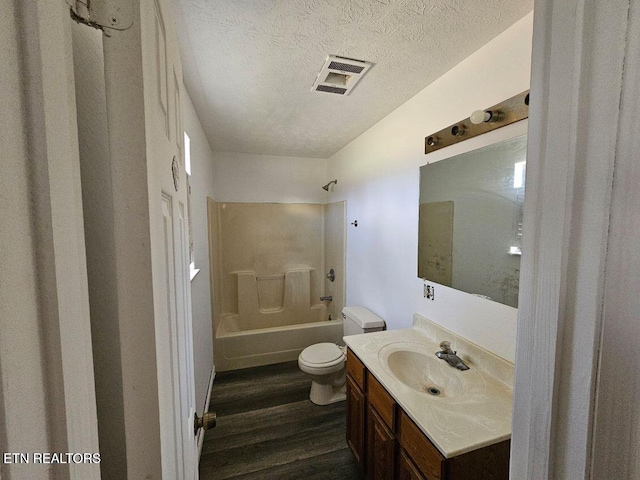 full bathroom with tub / shower combination, vanity, wood-type flooring, a textured ceiling, and toilet