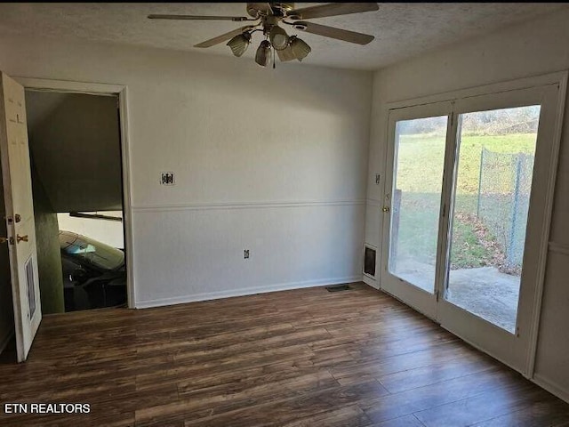 unfurnished room featuring ceiling fan, dark wood-type flooring, and a textured ceiling