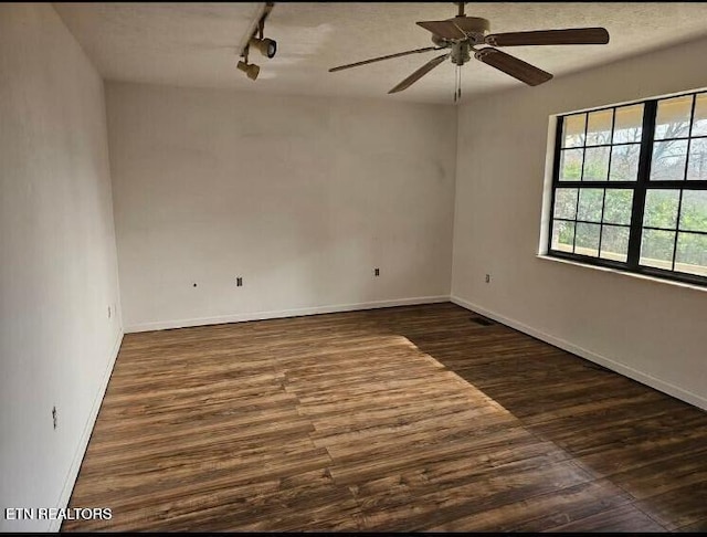 spare room with ceiling fan, dark hardwood / wood-style flooring, and rail lighting