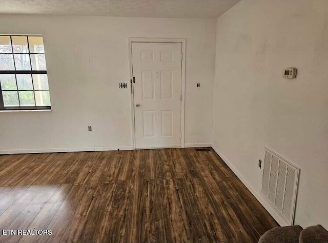 spare room featuring dark hardwood / wood-style floors and a textured ceiling