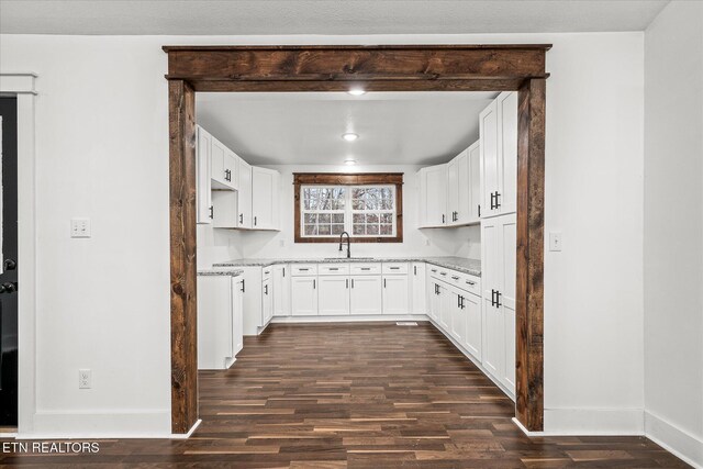 kitchen featuring sink, dark wood-type flooring, light stone countertops, and white cabinets